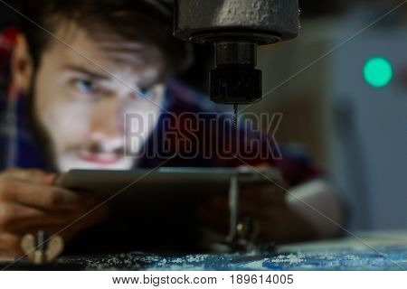 Engineer with touchpad looking at drill