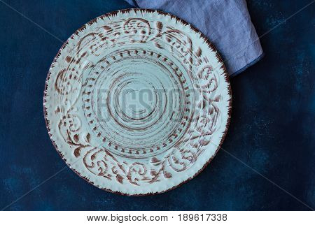 Blueish vintage empty plate linen napkin on dark blue concrete table top flat lay menu template copyspace top view styled