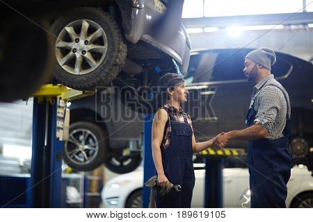 Female trainee handshaking with master of car-service