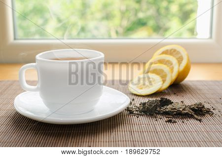 Cup of hot tea with lemon on window sill