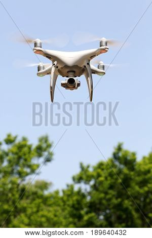 KAGAWA, JAPAN - MAY 20, 2017: White remote controlled Drone Dji Phantom4 Pro equipped with high resolution video camera flying in air and blue sky in the forest