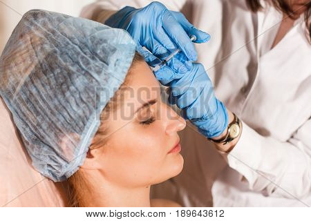 Woman gets injection in her face. Beauty woman giving injections. Young woman gets beauty facial injections in the cosmetology salon. Face aging injection. Aesthetic Medicine, Cosmetology.
