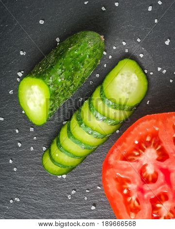 Fresh Green Sliced Cucumber And Tomato On A Black Stone Background.