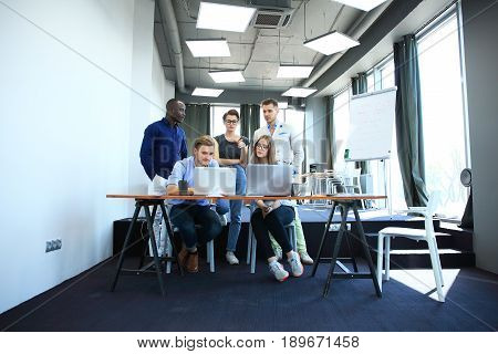 Teamwork concept.Young creative coworkers working with new startup project in modern office.Group of people analyze data on desktop computer.