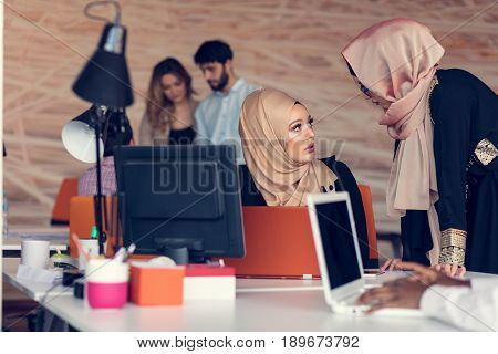 Two woman with hijab working on laptop in office