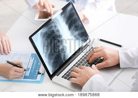 Asthma and health care concept. Doctors working at table, closeup. Chest x-ray scan on screen of laptop