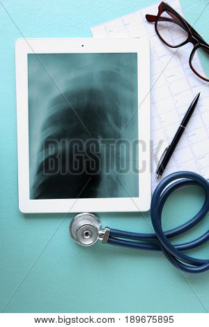 Asthma and health care concept. Tablet with stethoscope on color background. Chest x-ray scan on screen