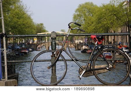 Bicycle Parked against the railing along one of the many canals in Amsterdam