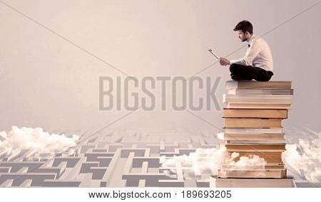 A businessman with laptop tablet in elegant suit sitting on a stack of books on top of sandy labirynth background concept