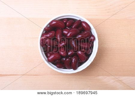 Heap of canned red kidney beans in the sauce in white bowl. vegetarian food. Phaseolus vulgaris