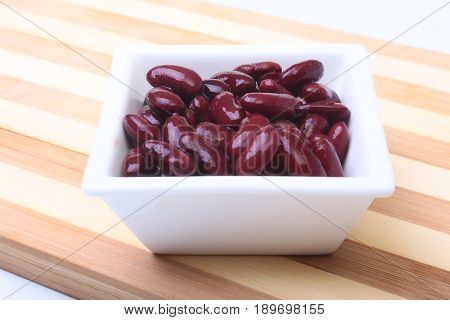 Heap of canned red kidney beans in the sauce in white bowl. vegetarian food. Phaseolus vulgaris