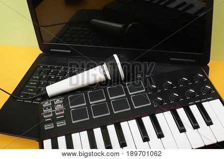 Musical instrument - MIDI keyboard laptop and vokal microphone for a karaoke on a flavovirent background.