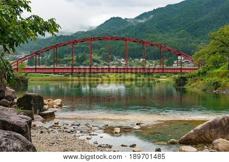 Japanese Countryside Landscape With Bright Red Bridge Over Kiso River