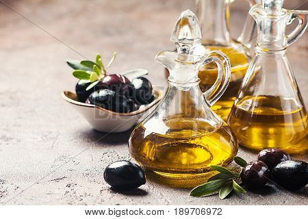 Olive oil in a glass bottle and olive branch on brown stone table
