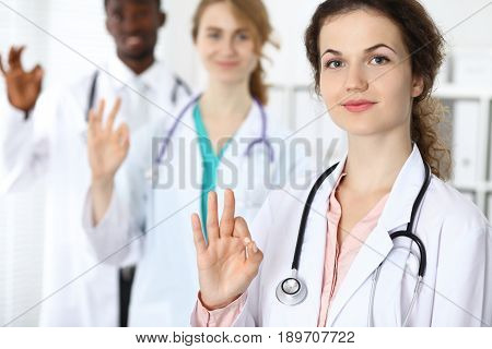 Medical team of confident doctors showing Ok sign and ready to help. Medicine and health care, insurance concept.