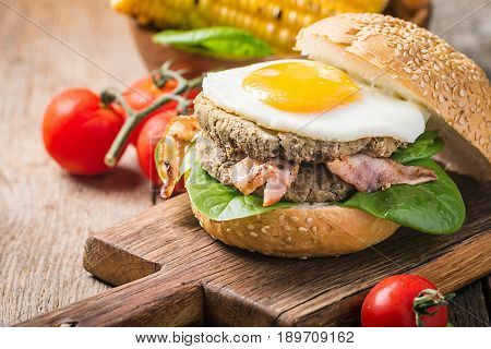 Homemmade Bacon Hamburger with fried Egg, Lettuce and lentil burger with a garnish of corn and tomatoes