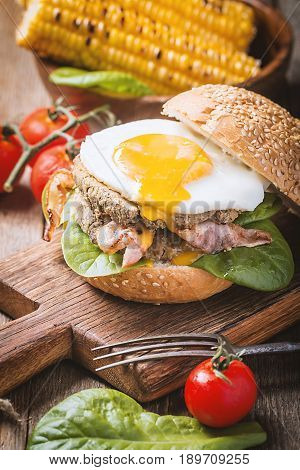 Homemmade Bacon Hamburger with fried Egg, Lettuce and lentil burger with a garnish of corn and tomatoes