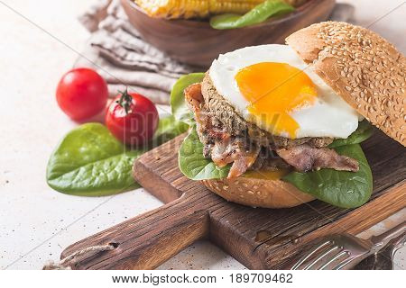 Homemmade Bacon Hamburger with fried Egg, Lettuce and lentil burger with a garnish of corn and tomatoes
