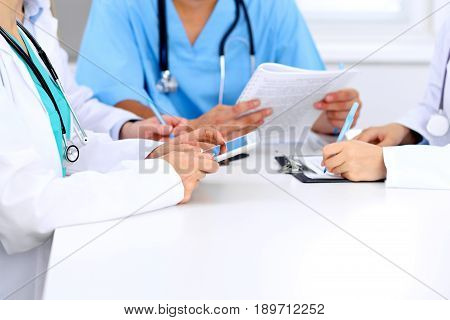 Group of doctors at medical meeting. Close up of physician using tablet computer