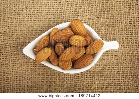 Almonds In White Ceramic Bowl On Sack Background