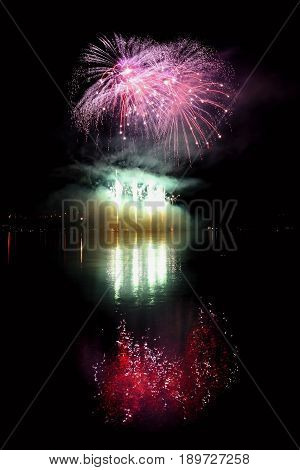 Beautiful colorful fireworks on the water surface with a clean black background. Fun festival and contest of Firefighters.