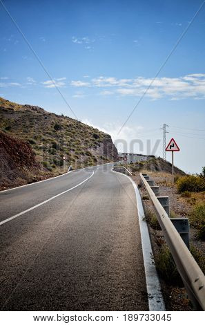 Warning sign in a red triangle on a mountain road
