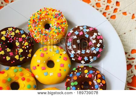 Yellow and brown donuts on a white plate
