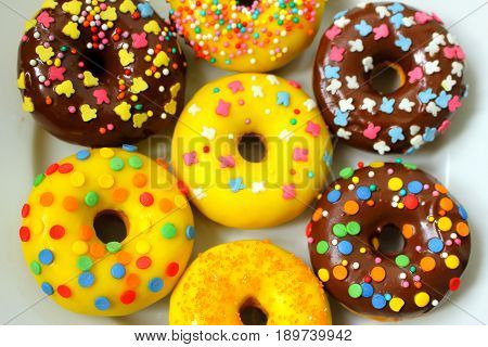 Yellow and brown donuts on a white plate
