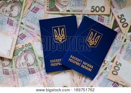 Two international passport of Ukrainians lie on pile of money from five hundred-pound banknotes. Passports for departure to Europe without visas. Visa-free regime for Ukraine.