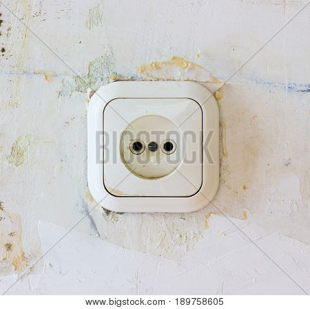 Old electrical outlet. An old plastic socket in a concrete wall during repair.