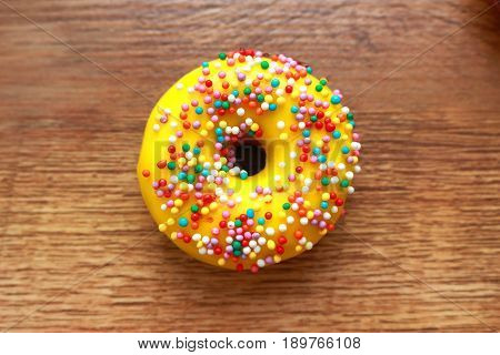 Single yellow donut on a wood background