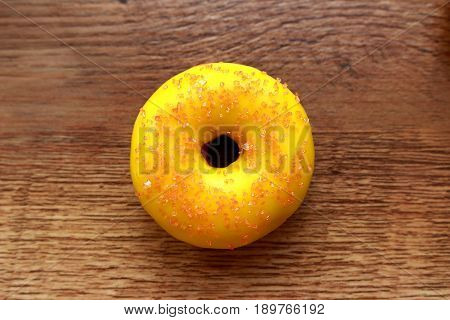 Single yellow donut on a wood background