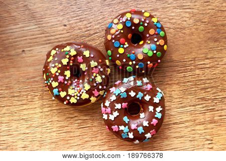 Three brown donuts on a wood background