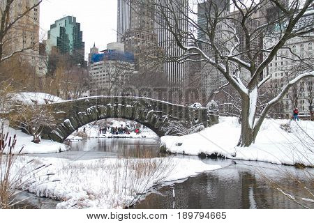 Buildings and Gapstow bridge over the icy lake and snow at Central Park