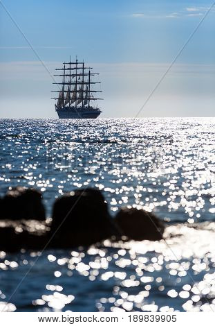 The world's largest sailing ship with five masts leaves at sunset in the open sea.