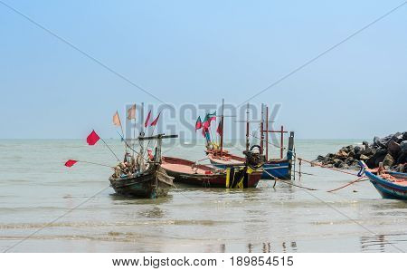 Small woodenl fishing boats (Longtail boats) anchored on beach in Thailand