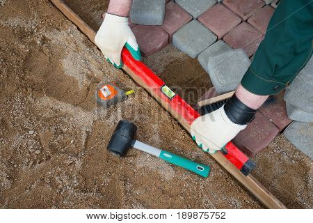 Mason worker making sidewalk pavement with stone blocks