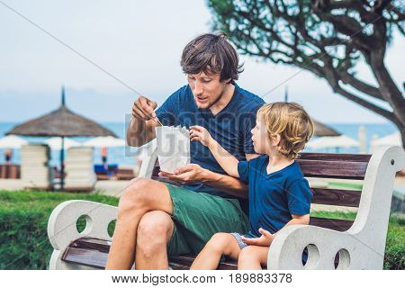 Father And Son Eat Fried Sweet Potatoes In The Park. Junk Food Concept