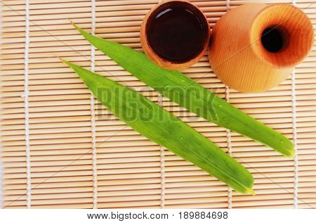 SAKE liqueur in a brown wooden bottle on a light brown background.