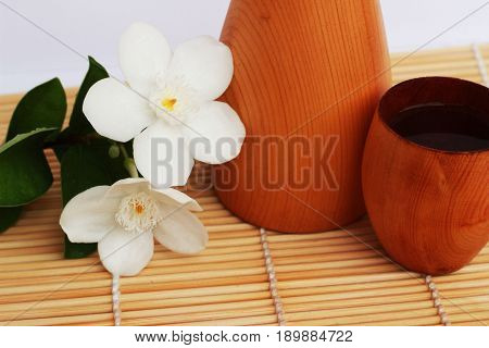 SAKE liqueur in a brown wooden bottle on a light brown background.