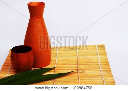 SAKE liqueur in a brown wooden bottle on a light brown background.