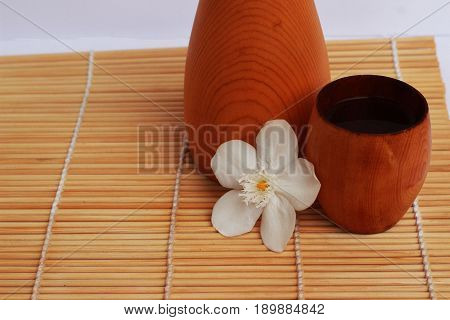 SAKE liqueur in a brown wooden bottle on a light brown background.