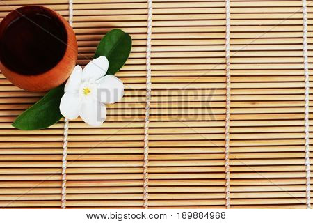 SAKE liqueur in a brown wooden bottle on a light brown background.