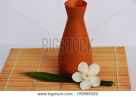 SAKE liqueur in a brown wooden bottle on a light brown background.