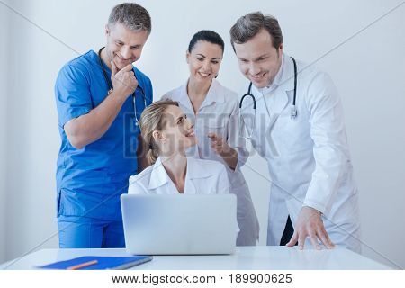 Need your point of view . Positive kind inventive practitioners working and using digital laptop at the hospital while enjoying conversation and sharing opinions