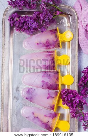 Popsicles with lemonade and fresh lilac flowers on siver tray