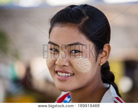 MANDALAY MYANMAR - JANUARY 17 2016: Unidentified young Myanmar girl with thanaka on her smile face is happiness. Thanaka is a yellowish-white cosmetic paste made from ground bark.
