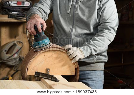 Carpenter grinding handmade merbau wood drum with sandpaper closeup