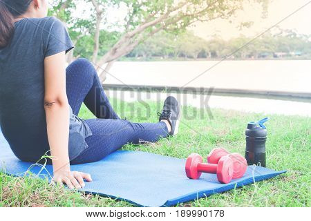 Asian woman in sport clothing sittng after exercise in the park Healthy lifestyle concept
