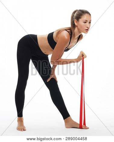 Motivation, fitness and people concept: Sporty woman  doing a exersize  with resistance band. Photo of young woman in fashionable sportswear on white background.  